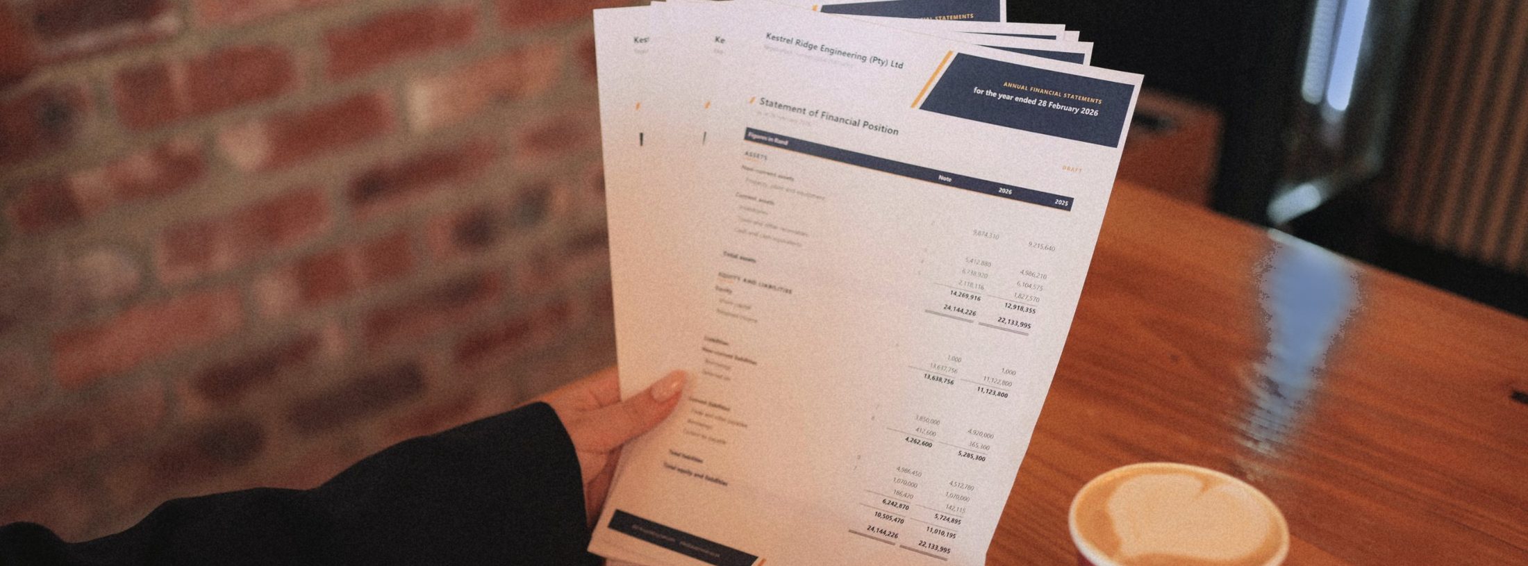 A completed set of annual financial statements, Statement of Financial Position page, held in hand